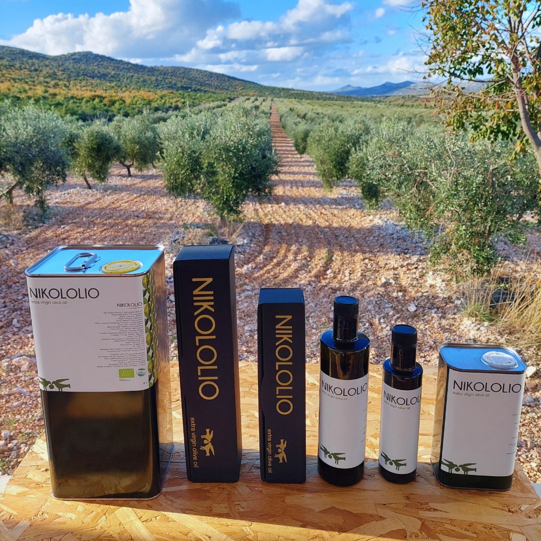 6 pakiranja maslinovog ulja od 5l do 0,25l. Podloga je drvena, a okolina je maslinik.