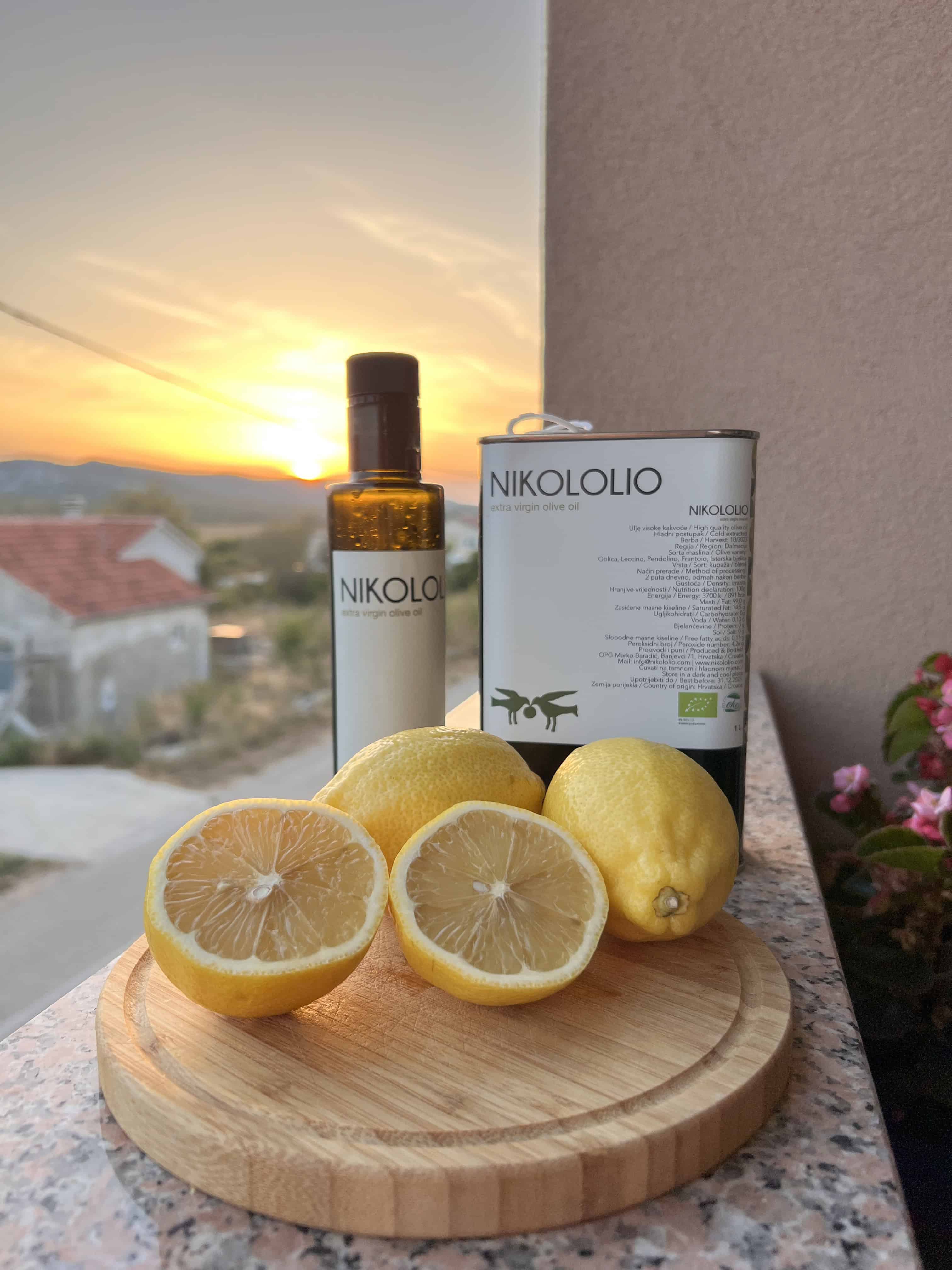 Dvije boce maslinovog ulja u limuni s pozadinom na kojoj je zalazak sunca.